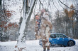 © standret - Holding woman. Happy couple having a walk in winter forest. Blue car is parked