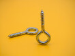 galvanised steel screw threaded eye bolts isolated on a plain yellow background