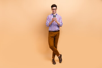 Sticker - Photo of handsome cheerful man wear striped stylish clothes writing telegram twitter post sms isolated on beige color background