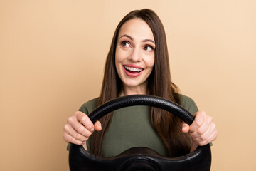 Poster - Photo of amazed young charming woman driving automobile distracted from the road and look in mirror isolated over beige color background