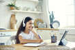 Preteen 12s girl in wireless headphones sit at table e-learning