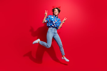 Sticker - Full body photo of jump overjoyed young lady showing double v sign winter holidays shopping season start isolated on red color background