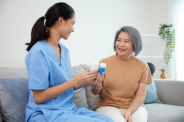 Wall Mural - caregiver or nurse giving and holding medicine pills bottle to senior woman on sofa