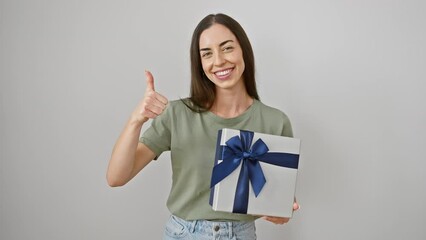 Poster - Radiant young hispanic woman showing ok sign, holding birthday gift package, happy and positive. gorgeous female in white isolated background exuding confident, cool joy in her cheerful smile.