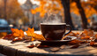 A steaming cup of coffee sits on an outdoor table amid fallen leaves, providing warmth on a chilly autumn morning