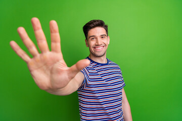 Sticker - Photo of optimistic friendly handsome guy with stubble dressed striped t-shirt give you highfive isolated on green color background