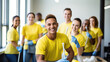 © Studio Nova - Smiling woman and man in a cleaning service uniform with colleagues in the background, indicating a professional cleaning team at work.