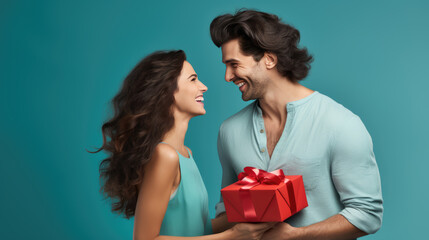 Canvas Print - Cheerful man and woman closely facing each other, smiling joyfully while holding a red gift between them.