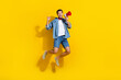 Full body photo of impressed overjoyed positive man dressed denim shirt fly hold megaphone scream yeah isolated on yellow color background