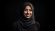 A portrait of a happy Muslim woman wearing a hijab, against a black background