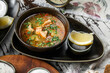 Fish soup with salmon, greens and lemon on bowl on rustic wooden background. Healthy food, top view