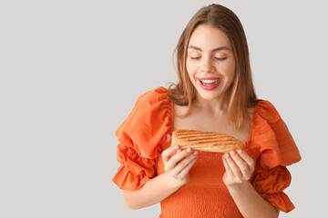 Canvas Print - Pretty young woman with tasty french hot dog on grey background