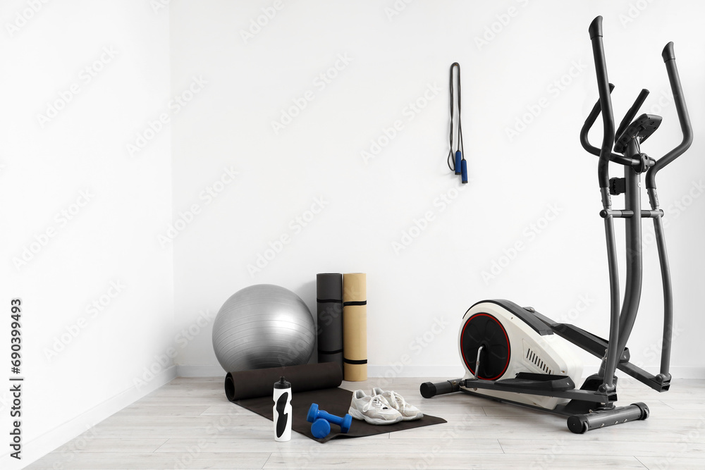 Different sports equipment near light wall in gym