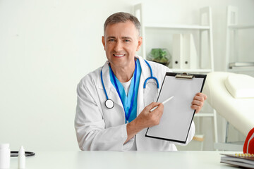 Wall Mural - Mature doctor video chatting at table in office