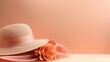 A fashionable wide-brimmed hat with peach ribbon and large flower on soft gradient background