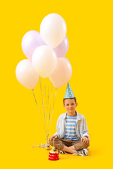 Wall Mural - Cute little boy with Birthday cake and balloons sitting on yellow background