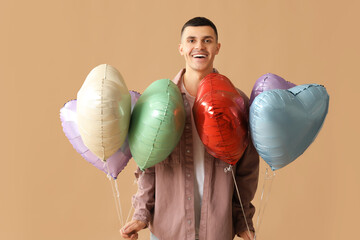 Poster - Young man with heart shaped air balloons on brown background