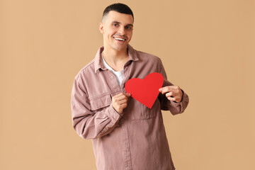 Poster - Happy young man with red paper heart on brown background