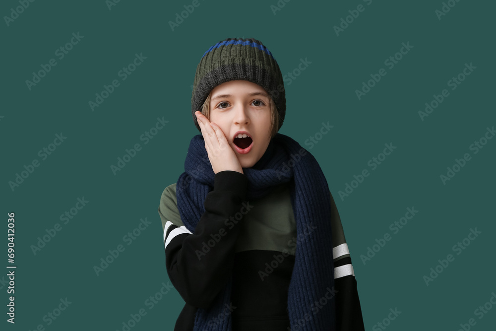 Cute little shocked boy in winter clothes on dark green background