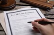 © New Africa - Woman signing last will and testament at table, closeup