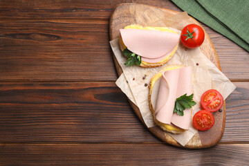 Wall Mural - Delicious sandwiches with boiled sausage, cheese and tomatoes on wooden table, top view. Space for text