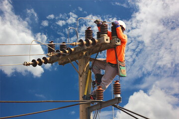 electric worker repair high voltage transmission lines on pole against blue sky