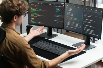 IT developer working online software development on pc monitors at modern home office on coding application screens, creating updated latest program firmware information version concept. Gusher.