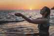 © olezzo - Woman enjoying the sea watre at sunset while sitting in a natural sea bath on the shore. Thalassotherapy and wellness