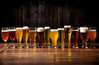 Cold mugs and glasses of beer on the old wooden table at the black background. Assortment of beer.