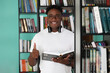 © Aleksandr - Attractive african student standing in library and giving thumbs up, enjoying interesting studies at higher education institution. Successful A-student, nerd gets an education