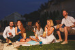 © Impact Photography - Friends drinking cocktails, eating popcorn and watching a movie in a backyard open air cinema
