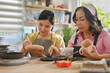 © saltdium - Asian Grandmother and young daughter painting ceramic crockery, Cottage industry with family activity concepts