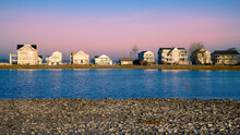 Peaceful Sunrise Seascape With Pink Fog Rising Behind The Beach Houses Along The Rocky Shoreline In New England Of America