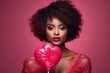 Portrait of beautiful African American girl in pink dress holding a giant pink lollipop in her hand. Charming black model with perfect makeup. Love and passion symbol. Valentine's Day concept.