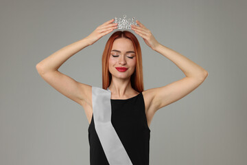 Poster - Beautiful young woman with tiara and ribbon in dress on light grey background. Beauty contest