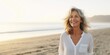 © Adriana - Smiling attractive beautiful caucasian senior mature woman posing at the beach looking at the camera