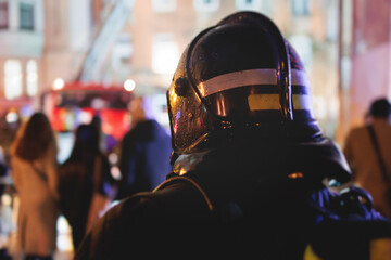 Group of fire men in protective uniform during fire fighting operation in the night city streets, firefighters brigade with the fire engine truck vehicle, emergency and rescue service