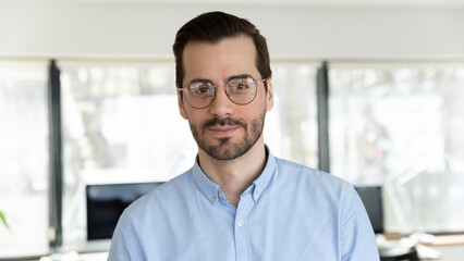 Wall Mural - Profile picture of young Caucasian man in glasses pose in office. Headshot portrait of confident 20s businessman in spectacles feel confident successful at workplace. Employment concept.