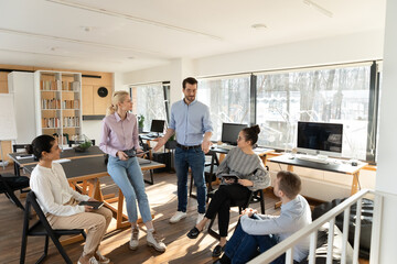 Wall Mural - Confident young Caucasian businessman lead head meeting with multiracial colleagues at casual office meeting. Multiethnic employees talk brainstorm at briefing at workplace. Teamwork concept.