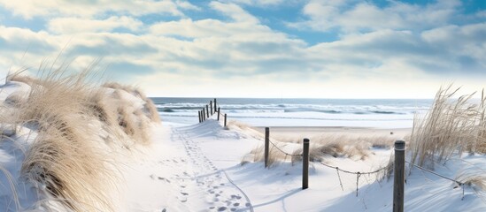 Poster - A wintry sandy beach view with snow and a distant boardwalk.