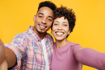 Wall Mural - Close up young couple two friends family man woman of African American ethnicity wear purple casual clothes together do selfie shot pov on mobile cell phone isolated on plain yellow orange background.