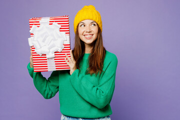 Sticker - Young woman wear green sweater yellow hat casual clothes hold present box with gift ribbon bow look aside on area isolated on plain pastel light purple background studio portrait. Lifestyle concept.