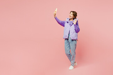 Wall Mural - Full body young woman wear purple vest sweatshirt casual clothes doing selfie shot on mobile cell phone post photo on social network isolated on plain pastel light pink background. Lifestyle concept.