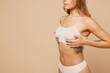 © ViDi Studio - Close up cropped side view young nice lady woman with slim body perfect skin wear nude top bra lingerie stand hold touch breast isolated on plain pastel beige background. Lifestyle diet fit concept.