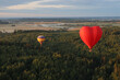 Two hot air balloons with people are flying over forests and fields in the morning at dawn