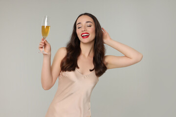 Poster - Christmas celebration. Beautiful young woman with glass of champagne on grey background