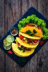 Poster - Tacos with ground beef, avocado, corn and fresh vegetables on wooden table 