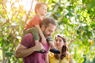 Wall Mural - Happy Caucasian family spending time traveling together, green trees in sunlight.