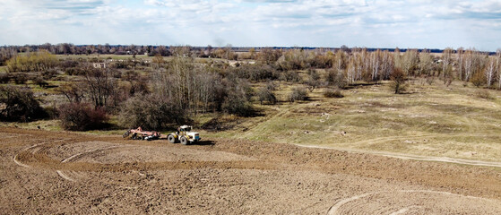 Wall Mural - Agricultural machinery in a field near a small grove, aerial view. Agricultural land.