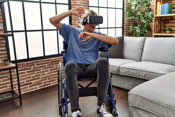 Poster - Young blond man playing video game using virtual reality glasses sitting on wheelchair at home